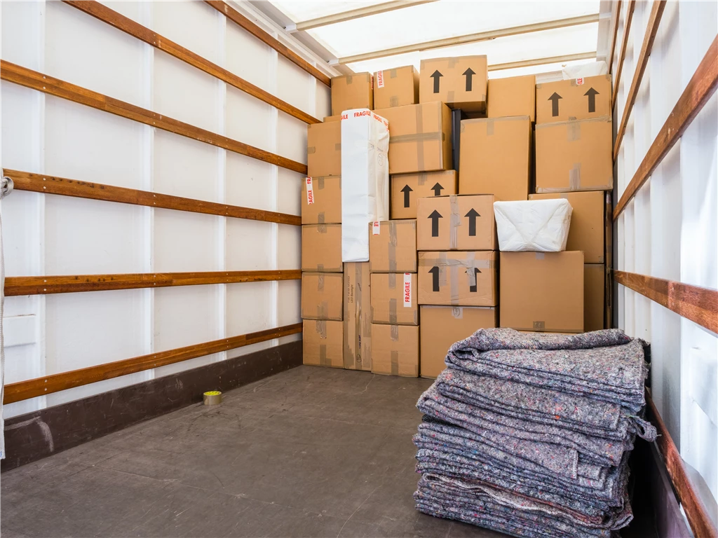 Interior of a moving truck with boxes and blankets organized for shipment.