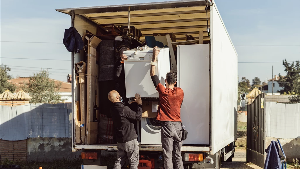 Family lifting washer into truck with Move It Naples moving company