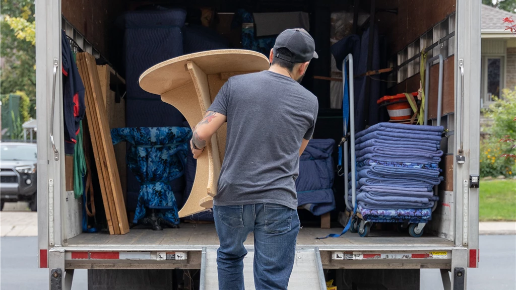 Move It Naples team carrying furniture into a moving truck on a city street.